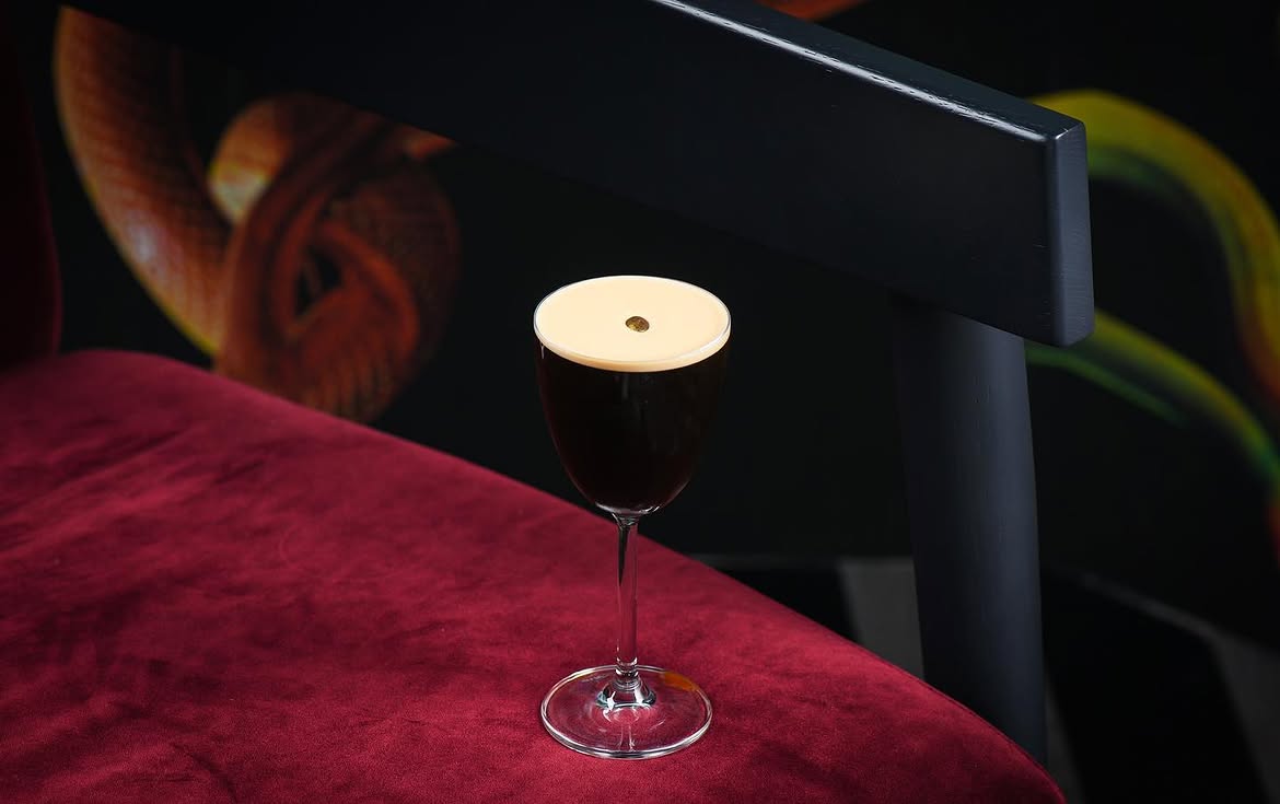 Cocktail against gallery wall of framed art